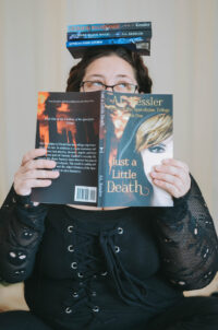 Photo of AL Kessler with book hiding face and books on top of head.